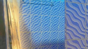 Un baño con lavamanos, espejo y baldosas estampadas.