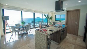 Une cuisine moderne dotée d’un grand îlot central, d’un coin repas et offrant une vue sur la mer.