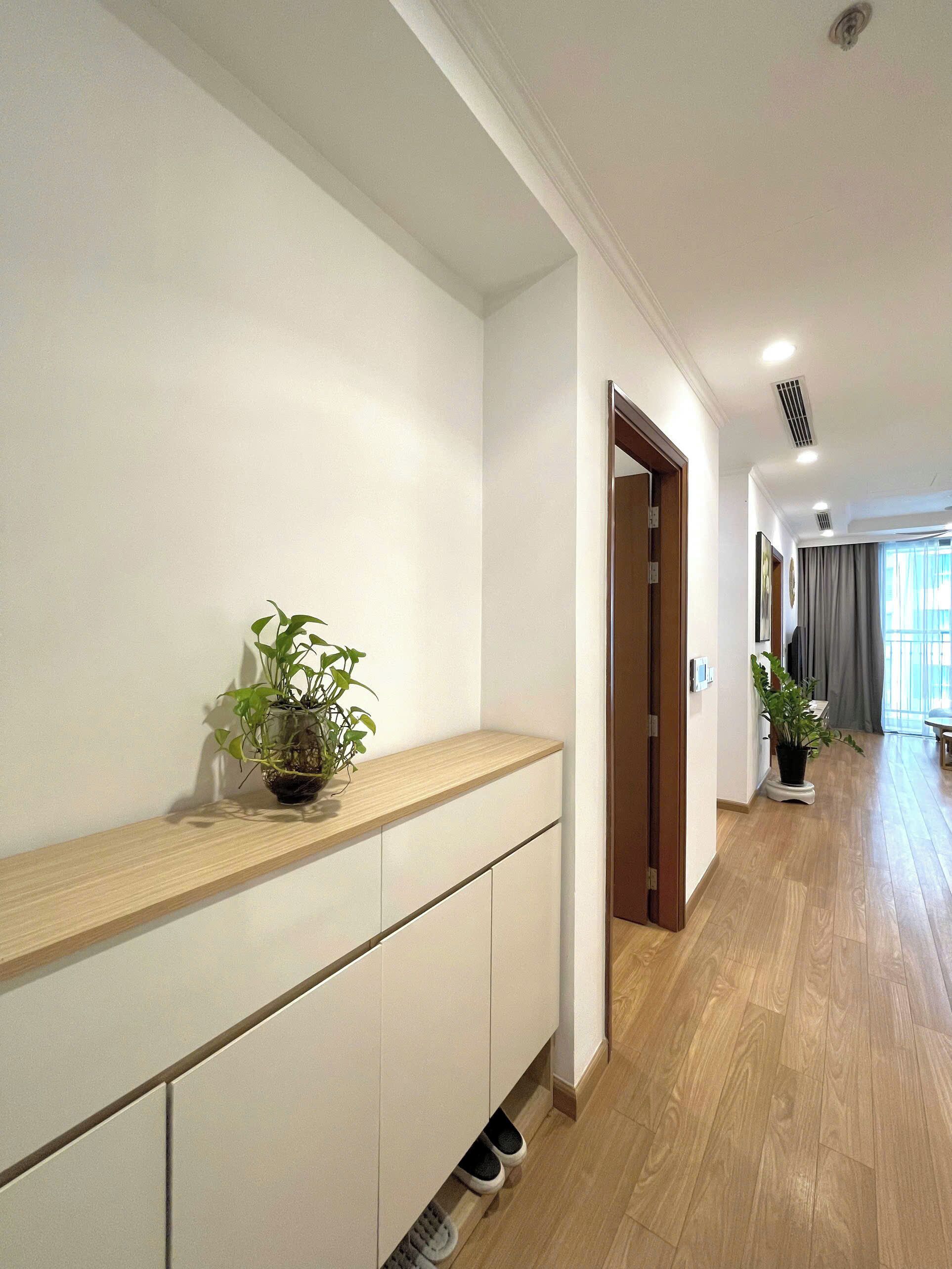 A hallway with a wooden bench, potted plants, and a door leading to another room.