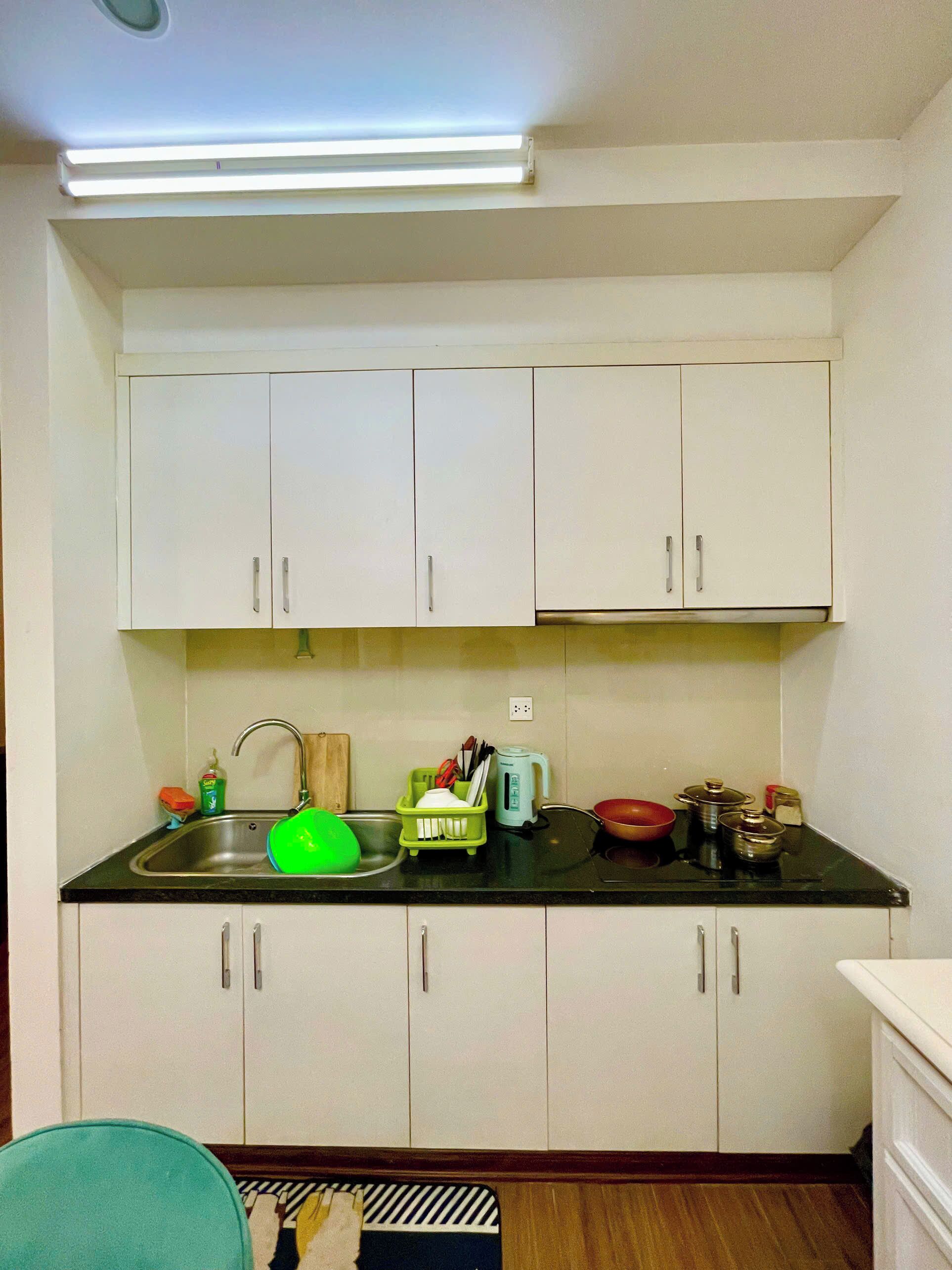 Une cuisine de taille réduite avec des meubles blancs, un plan de travail noir et des appareils électroménagers de base.