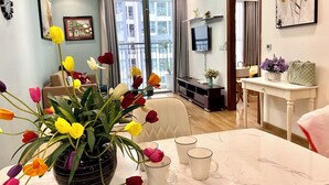 A modern living room with a dining area, a large window, and a chandelier. - HMH- Vinhomes TIme City - Park Hill  (Hanoi)