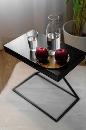 A small table with a glass bottle, a glass of water, and two apples on a tray. - Absyntapart Krawiecka - parking w cenie (Wroclaw)