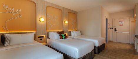 A hotel room with two beds, wooden headboards, and a small kitchenette.