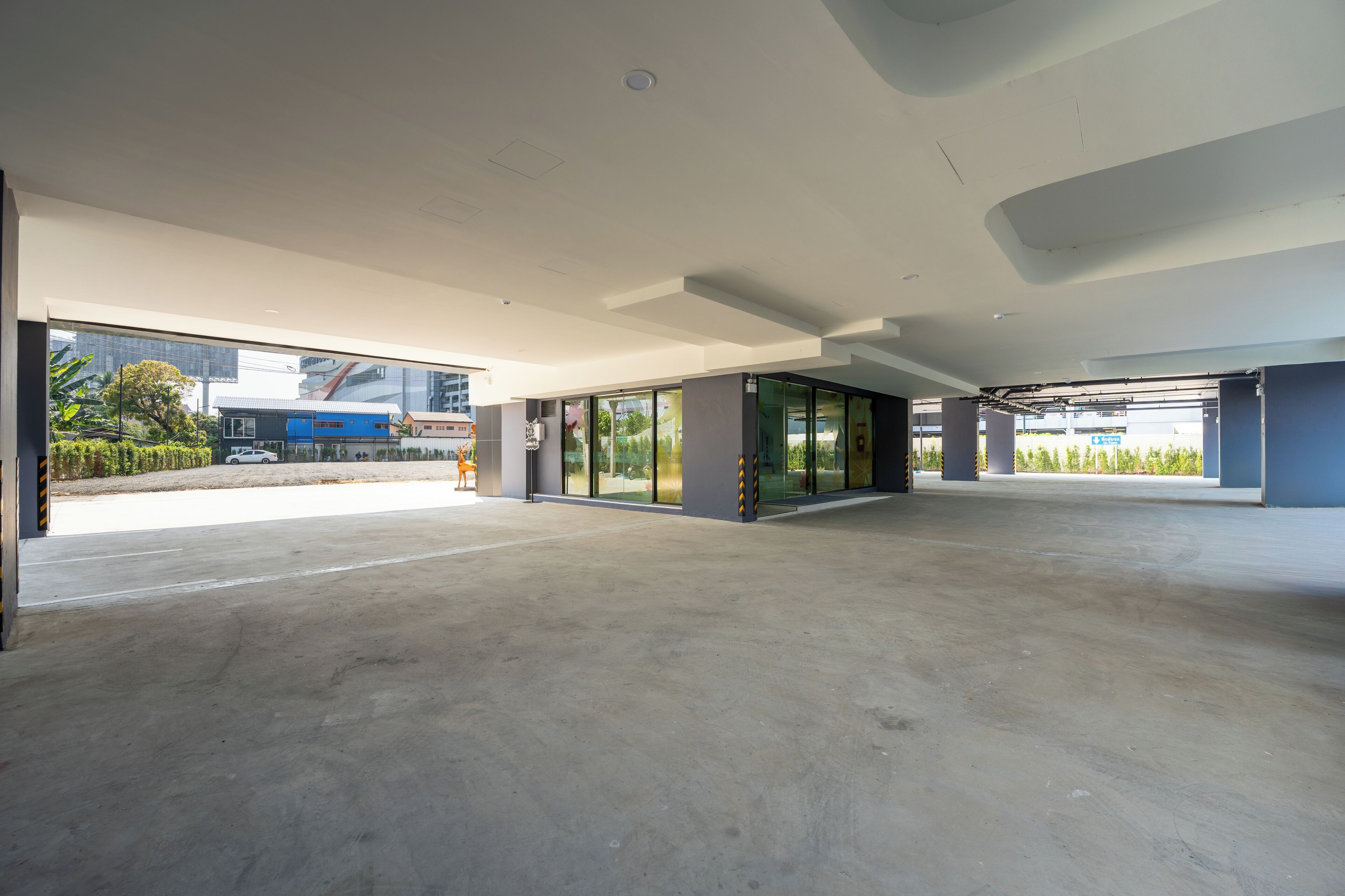 An empty modern building with large glass windows and a concrete floor.