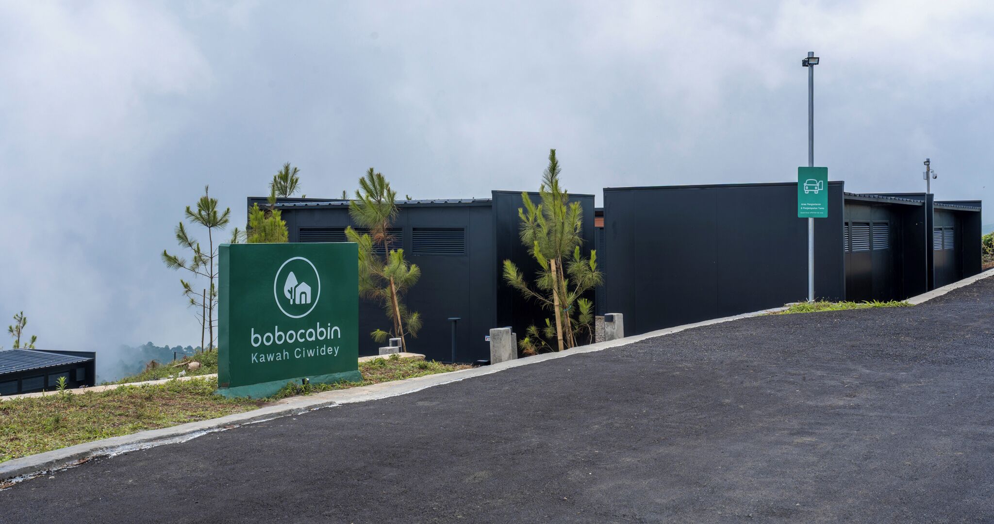 A Bobocabin Kawah Ciwidey sign with a modern building in the background.
