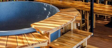A wooden outdoor seating area with a circular stone table.