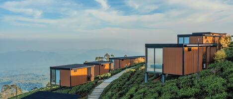 Une propriété moderne située sur une colline, comprenant plusieurs chalets, chacun doté de grandes fenêtres et d’un design minimaliste.