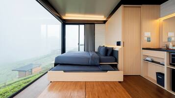 A modern bedroom with a built-in bed, a small kitchen area, and a view of the city.