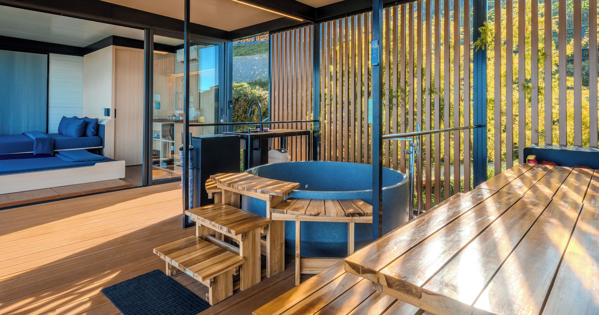 Un espace de vie extérieur moderne, doté d’un jacuzzi, de tables en bois et d’un canapé.
