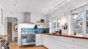 A modern kitchen with white cabinetry, a blue and black backsplash, and wooden countertops.