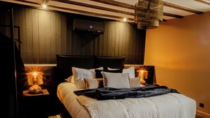 Een moderne slaapkamer met een groot bed, twee bedlampen, een houten hoofdeinde en een plafondlamp.