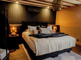 Un dormitorio moderno con una cama grande, dos lámparas de noche, un cabecero de madera y una lámpara de techo.