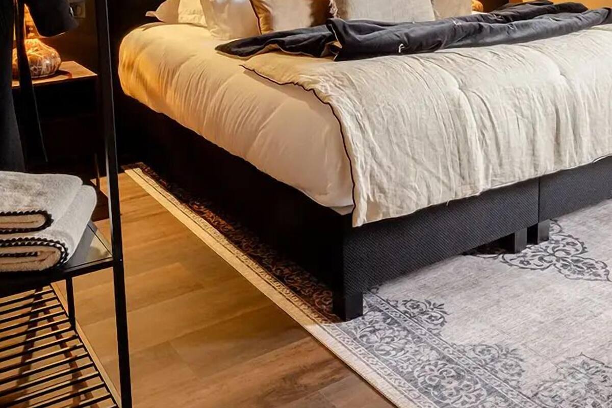 Quarto moderno com uma cama grande, teto de madeira, ar condicionado fixado na parede e luminária pendente.