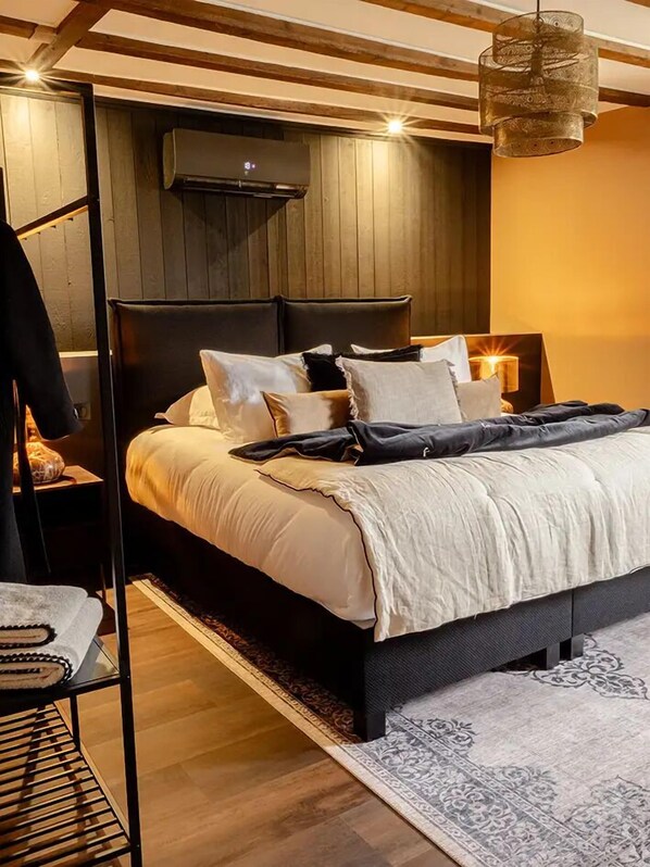 Un dormitorio moderno con una cama grande, techo de madera, aire acondicionado de pared y lámpara colgante.