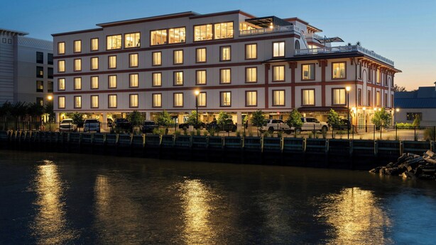 Hotel de diversos pisos amb un balcó al pis superior, situat al costat d'una massa d'aigua.