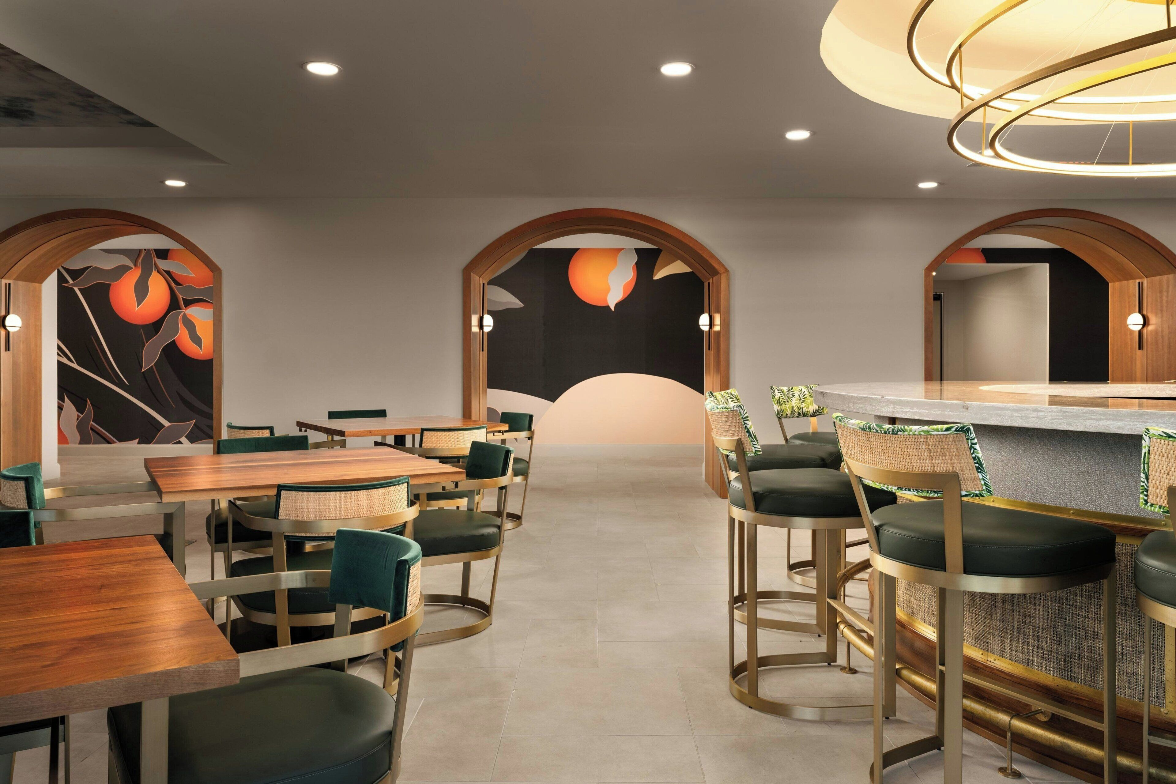 A modern restaurant with wooden tables and chairs, a bar area, and decorative wall art.