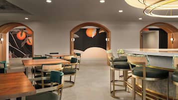A modern restaurant with wooden tables and chairs, a bar area, and decorative wall art.