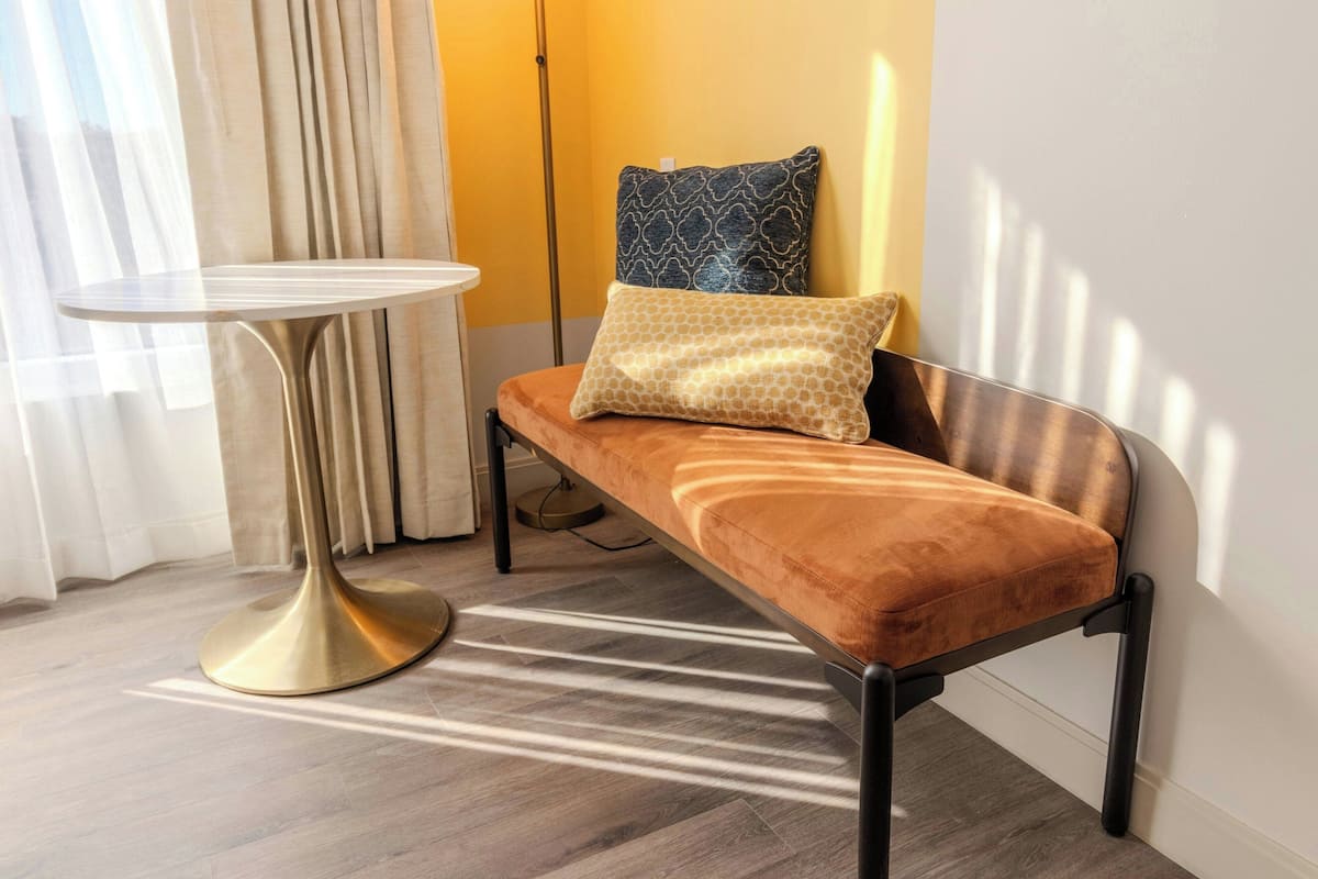 A modern room with a bench, a small round table, and a patterned pillow.