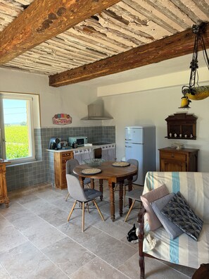 Una cocina rústica con una mesa de madera, sillas y una lámpara colgante.