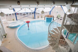 Ein Hallenbad mit Wendeltreppe, einem roten Rettungsring und einer blauen Sitzgelegenheit.