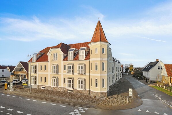 A multi-story building with a prominent tower, large windows, and a red roof.