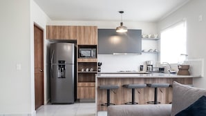 A modern kitchen with a built-in refrigerator, wooden cabinets, a bar area with stools, and a window providing natural light. - Puerto Vallarta Calm Getaway with Pool  (Puerto Vallarta)