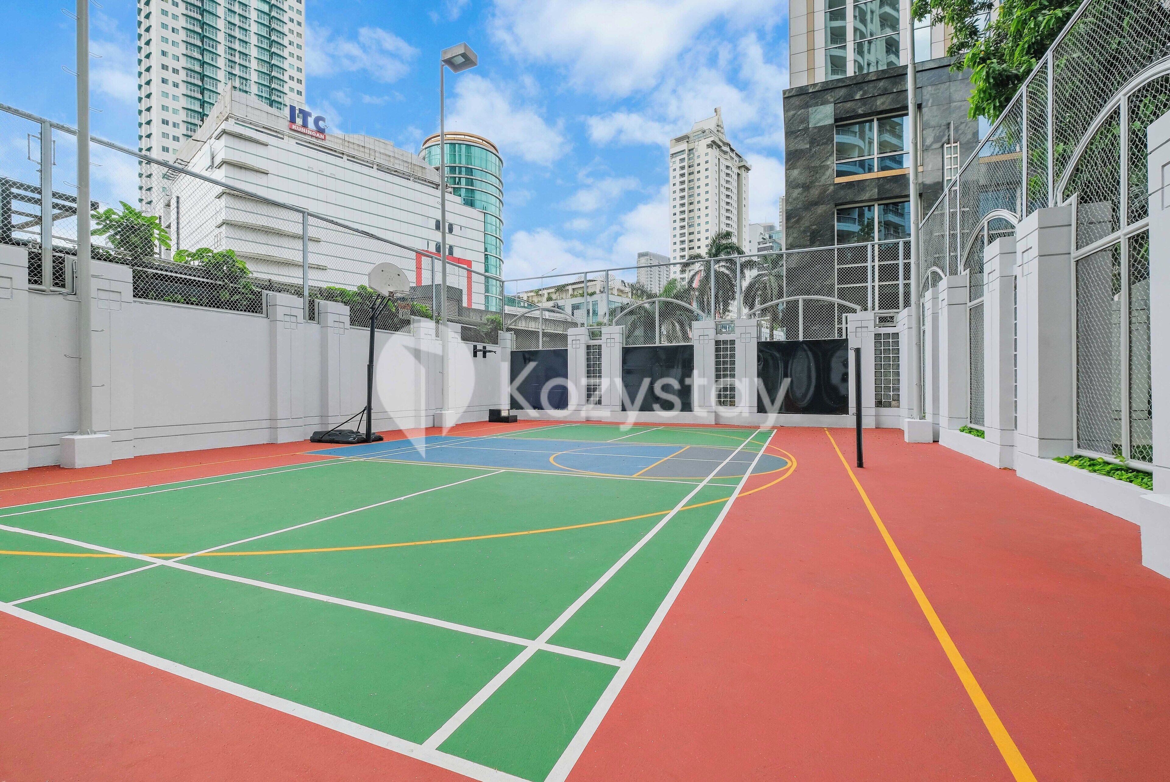 An indoor sports court with a green and red surface, surrounded by white walls and metal fencing.