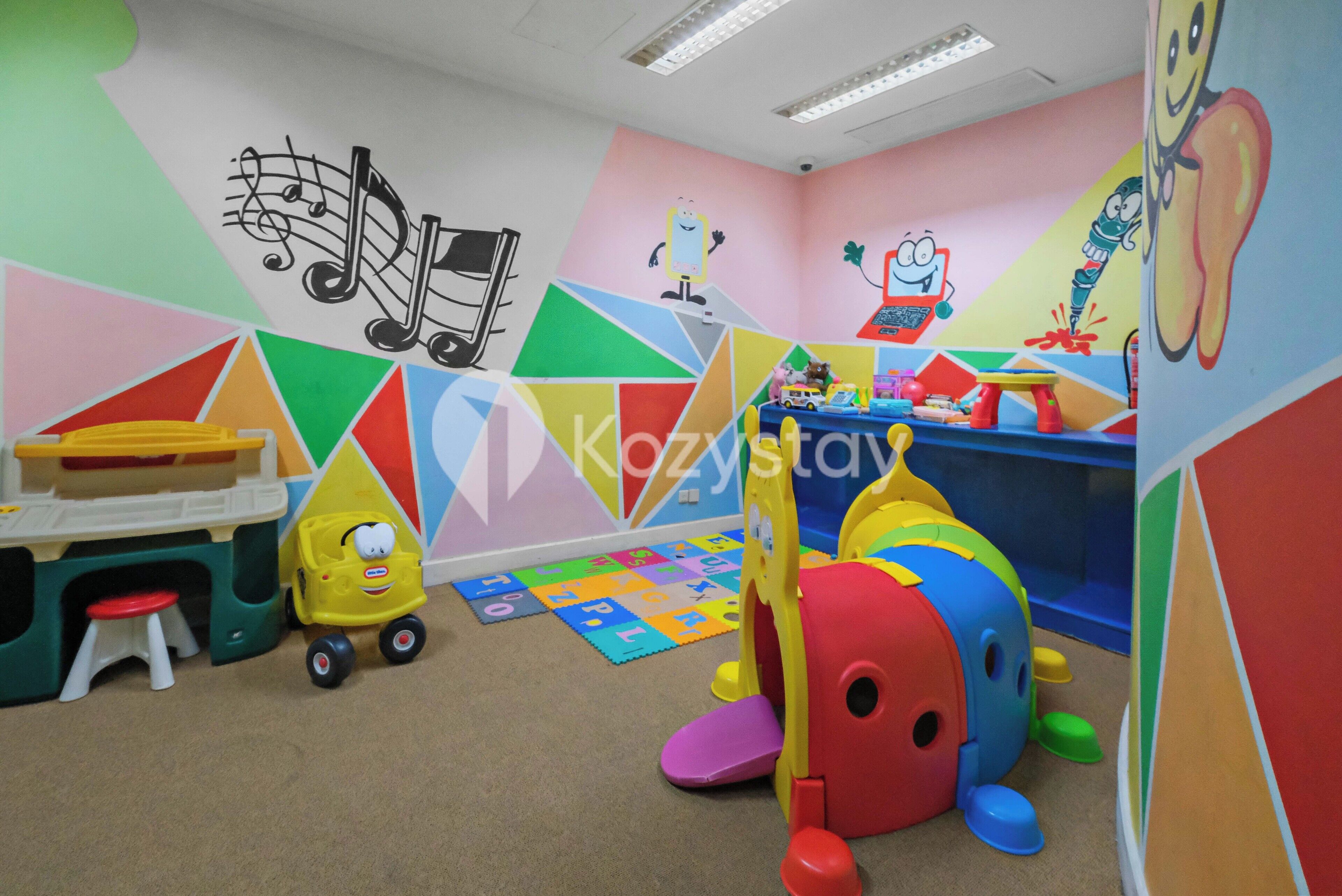 Un salón infantil lleno de color, con una mesa de juegos, juguetes y decoraciones educativas en las paredes.