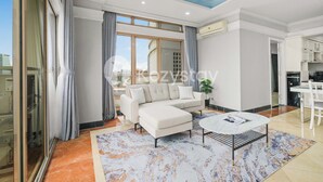 A modern living room with a sofa, a coffee table, and a view of the city. - Camila by Kozystay - Kuningan (Jakarta)