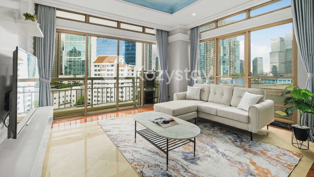 A modern living room with a large sofa, a coffee table, and a view of a cityscape through large windows. - Camila by Kozystay - Kuningan (Jakarta)
