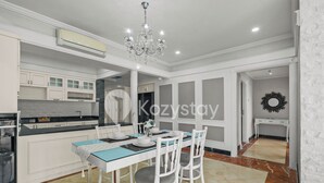 A modern kitchen with white cabinetry, a dining table set for four, and a chandelier. - Camila by Kozystay - Kuningan (Jakarta)