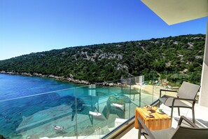 A glass balustrade overlooking a clear blue sea with boats, a wooden table, and two chairs on a balcony. - VILLA BY THE SEA (Ljubljeva)