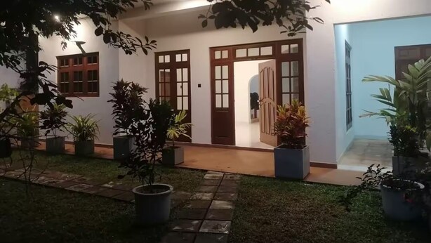 A modern building with a covered entrance, potted plants, and a well-maintained lawn.