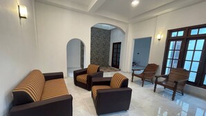 A spacious living area with modern sofas, a wooden chair, and a stone wall.