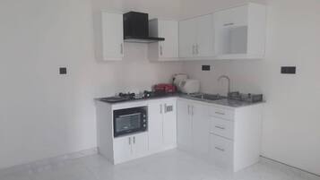 A modern kitchen with white cabinets, a built-in oven, a microwave, and a gas stove.