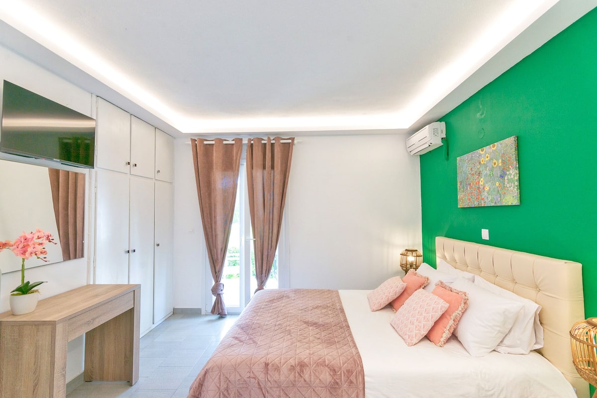 A bedroom with a bed, a bedside table, a mirror, and a green wall.