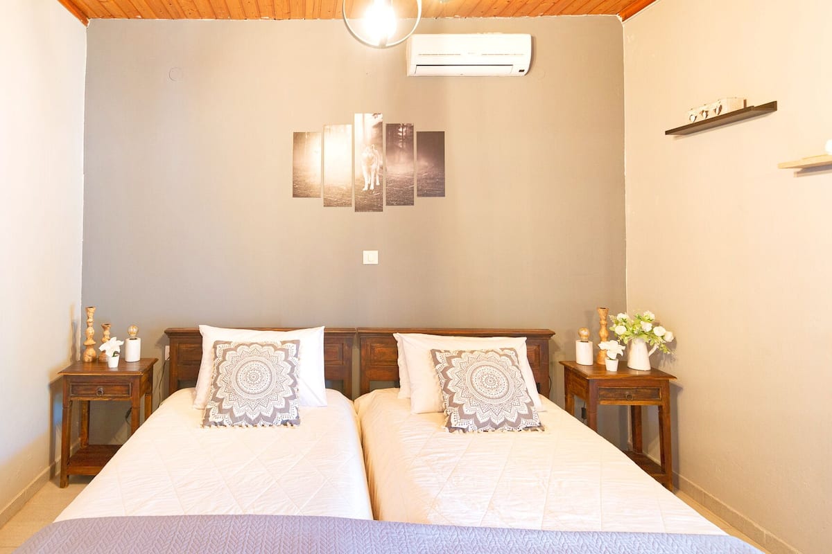 A double bed with two nightstands, a wall-mounted air conditioner, and a shelf with decorative items.