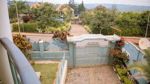 A gated residential area with a paved driveway, a satellite dish, and lush greenery. - Wins Homes (Kigali)