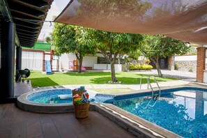 A swimming pool with a shaded area, a grassy yard, and a tree. - Family house in Oaxtepec Pool & Hot tub (Yautepec)