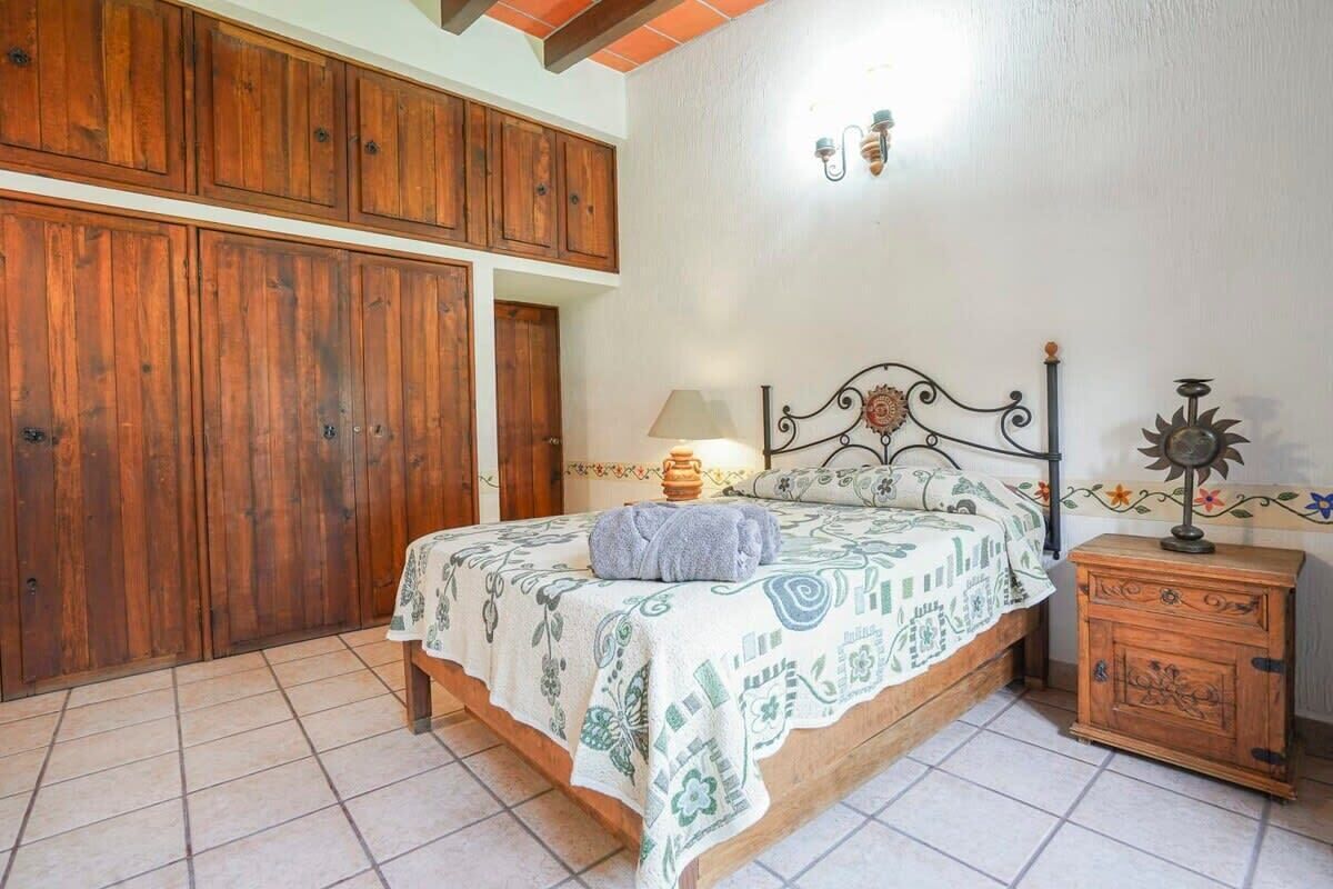 Une chambre à coucher avec un lit, une armoire en bois et une table de chevet avec une lampe.