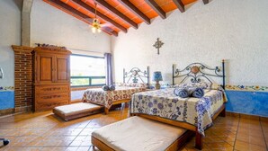 Een slaapkamer met twee bedden, een houten dressoir en een bakstenen muur.