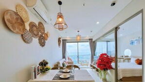 Un'elegante zona pranzo con tavolo imbandito per due, una grande finestra vista città e un balcone che si affaccia sul mare.