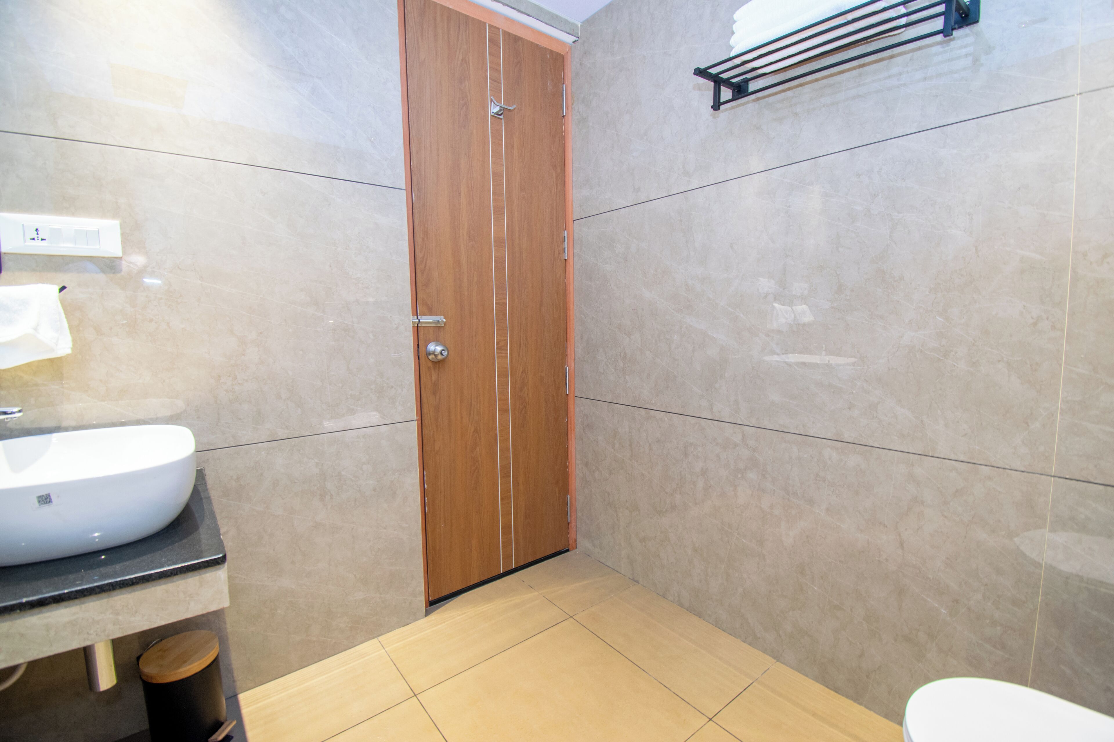 A bathroom with a wooden door, a white sink, and a toilet.