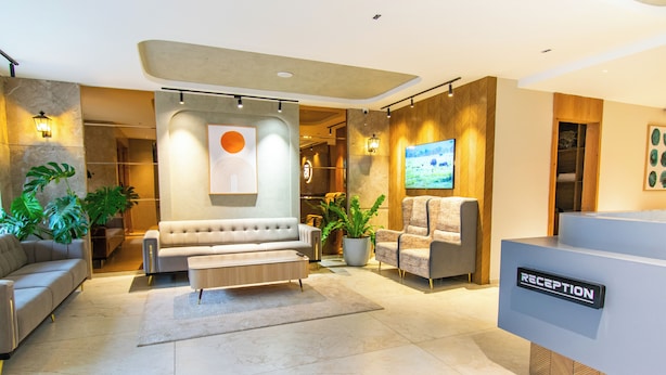 A modern reception area with a sofa, armchairs, and a reception desk. - Hotel Sing 65 (Bengaluru)