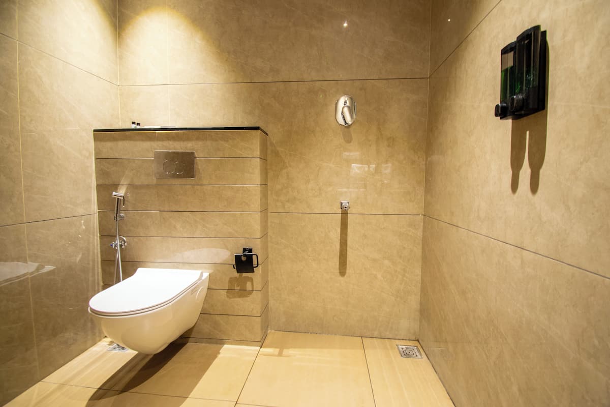 A modern bathroom with a toilet, shower, and hand dryer.
