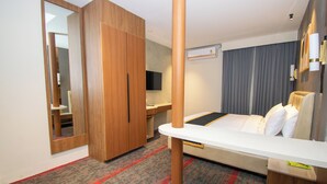 A hotel room with a bed, a desk, a wardrobe, a mirror, and a television. - Hotel Sing 65 (Bengaluru)