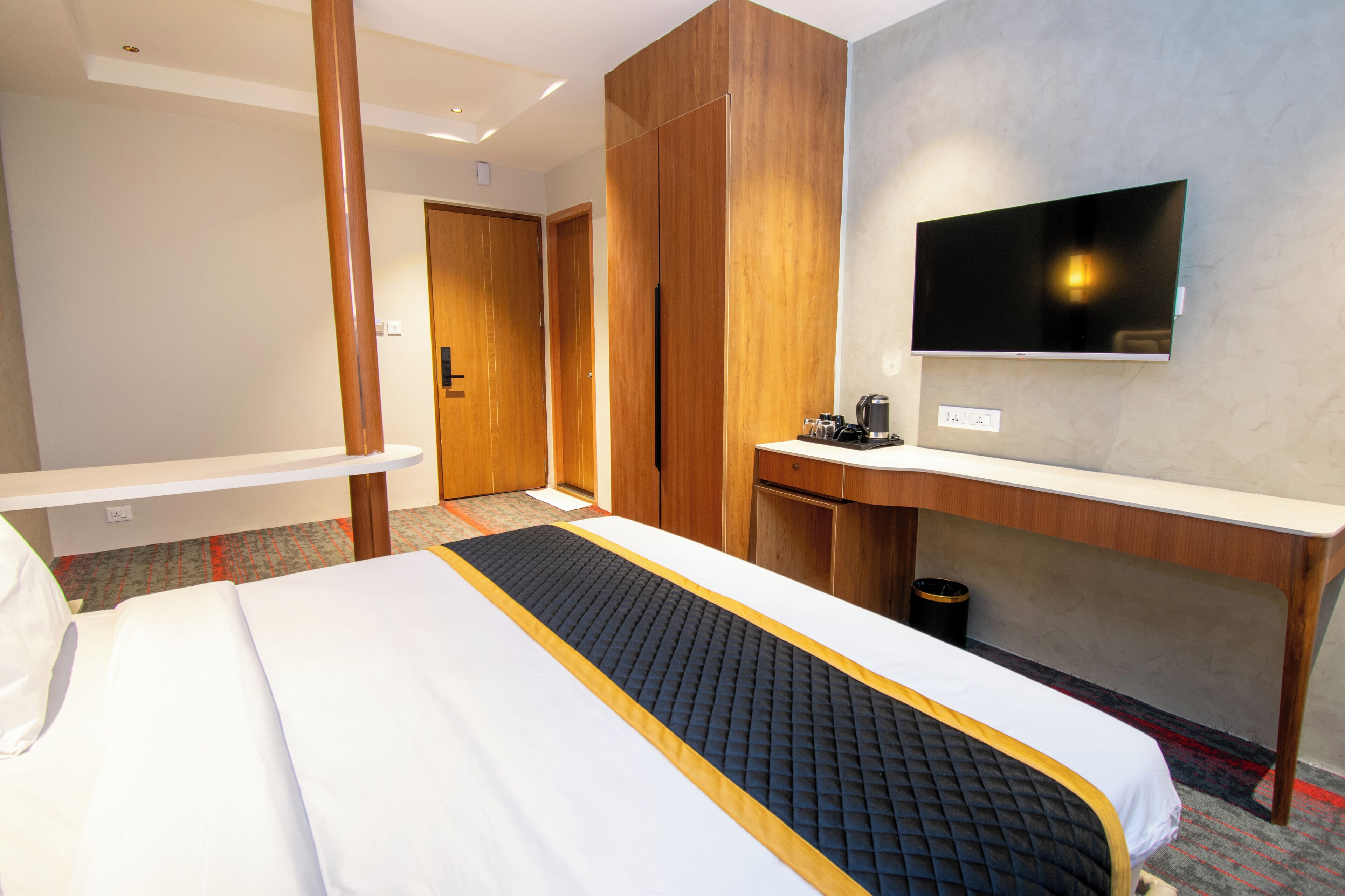 A hotel room with a bed, a desk, a television, and a wardrobe.