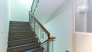 A staircase with a wooden handrail and metal balusters, leading to an upper floor. - Hotel Sing 65 (Bengaluru)