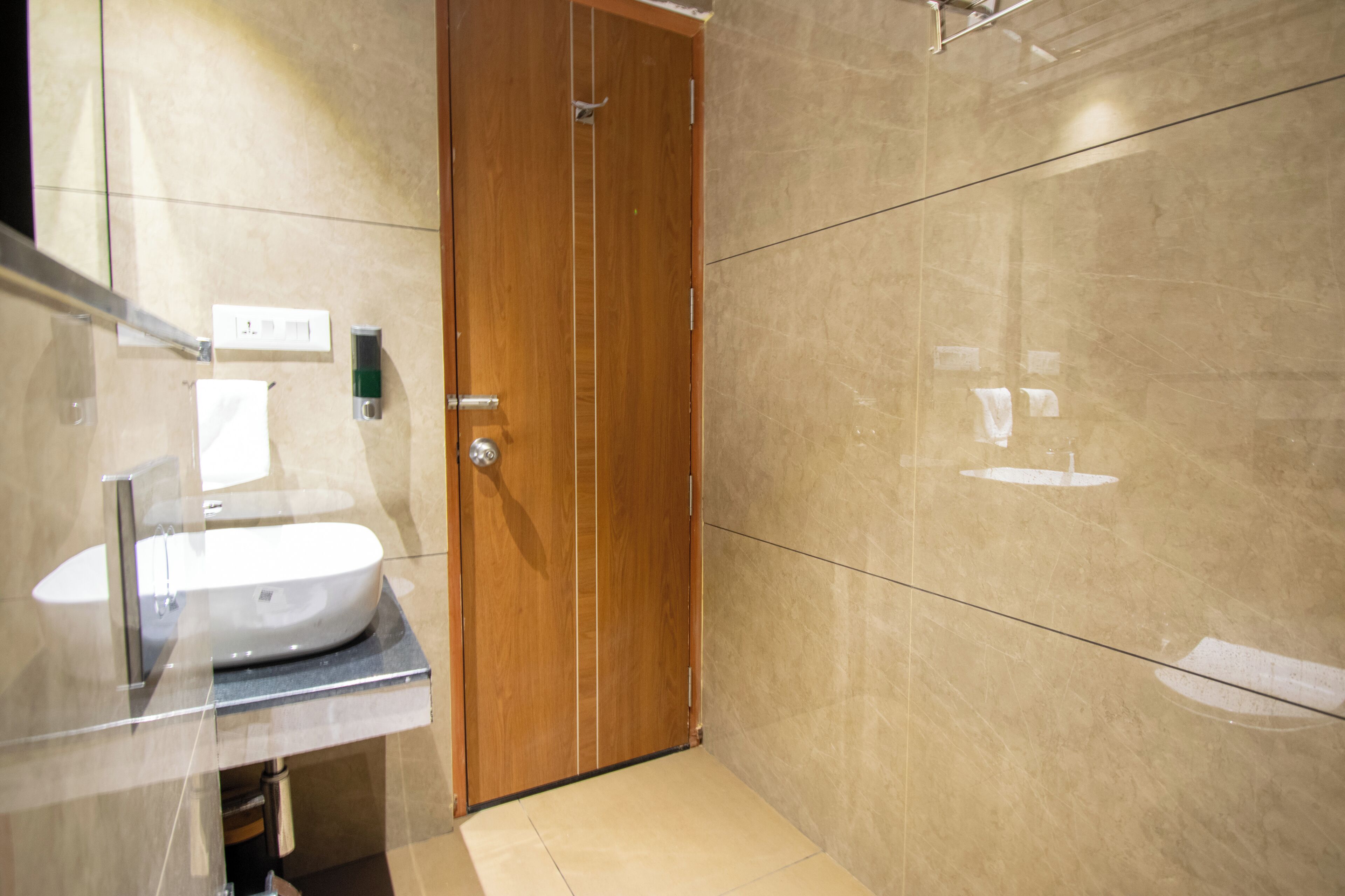 A modern bathroom with a wooden door, a sink, and a mirror.