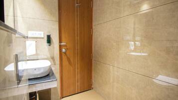 A modern bathroom with a wooden door, a sink, and a mirror.